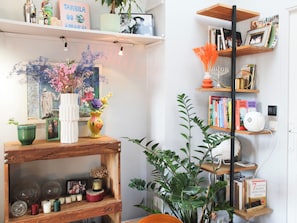 A room with a wooden shelf holding books, a white vase with flowers, and a framed picture. - Charming 66 sqm attic flat, Paris (Paris)