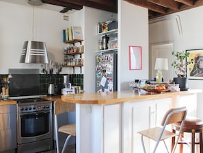 A kitchen with a stove, oven, and bar area with chairs. - Charming 66 sqm attic flat, Paris (Paris)