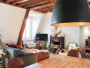 A cozy living room with a wooden table, chairs, a sofa, a fireplace, and a television. - Charming 66 sqm attic flat, Paris (Paris)