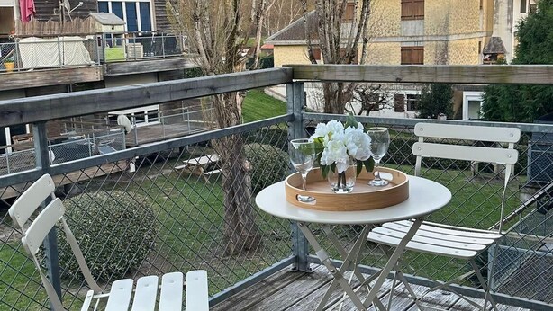 A deck with a table and chairs, surrounded by a fence, overlooking a residential area with houses and bare trees. - Peaceful Verdant Haven in Le Teic (Le Teich)