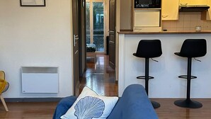 A room with a bed, a chandelier, a kitchenette, and a view through an open door. - Peaceful Verdant Haven in Le Teic (Le Teich)