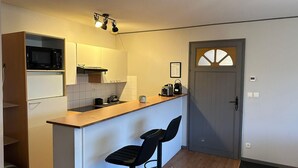 A compact kitchen with a microwave, toaster, and a small island with bar stools. - Peaceful Verdant Haven in Le Teic (Le Teich)