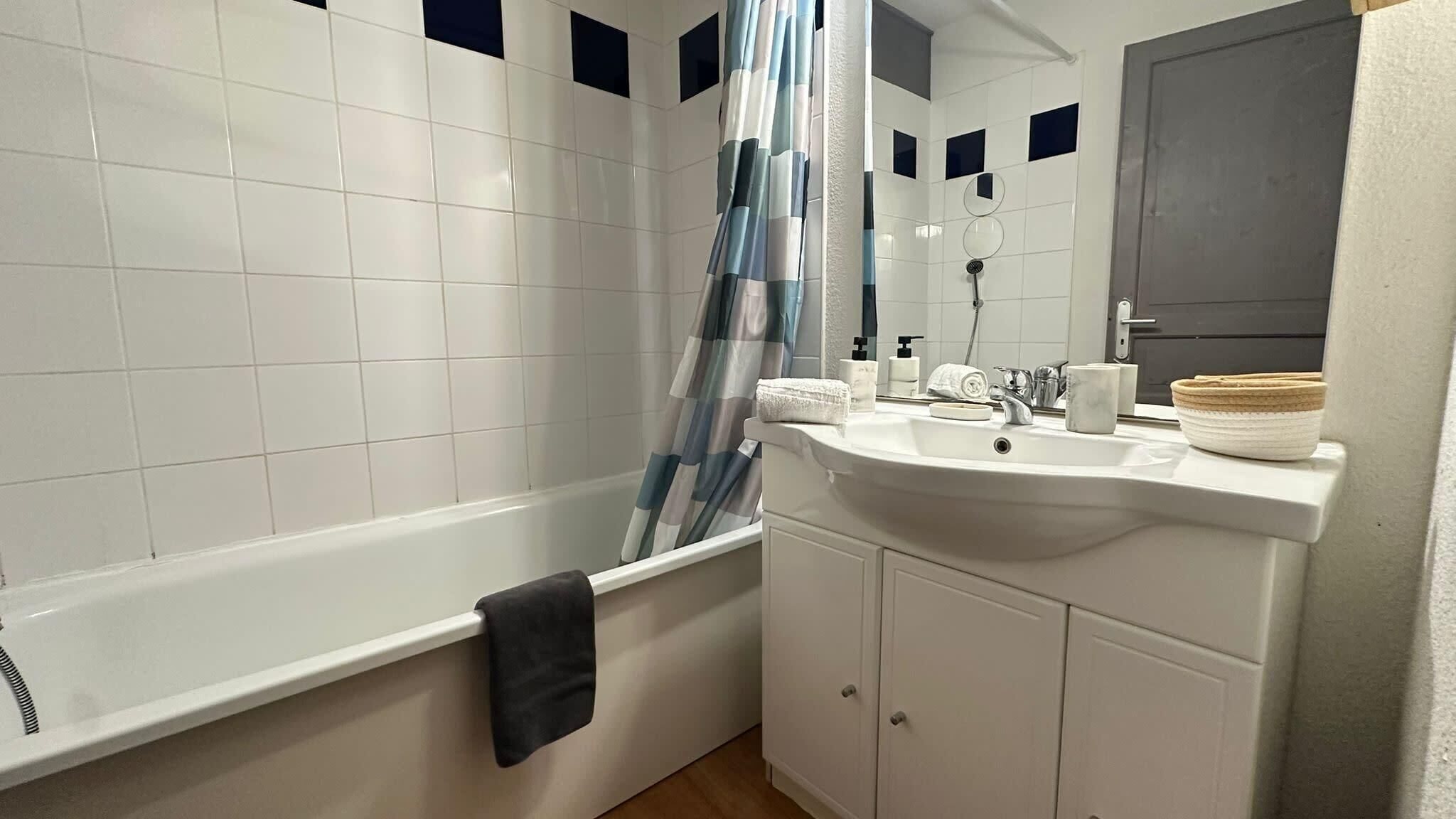 A bathroom with a bathtub, a sink, a mirror, and a towel rack.