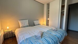 A bedroom with a bed, bedside lamps, a small table, and a closet. - Peaceful Verdant Haven in Le Teic (Le Teich)