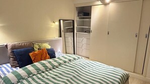 Un dormitorio con cama, armario y espejo.