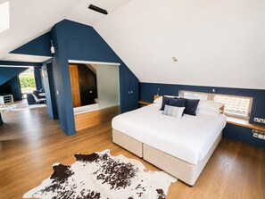 A bedroom with a large bed, a cowhide rug, and a view of the outdoors. - Print Room 2 at Strattons Hotel (Hingham)