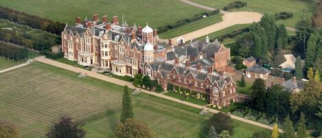 A large, historic building with multiple wings and a formal garden.