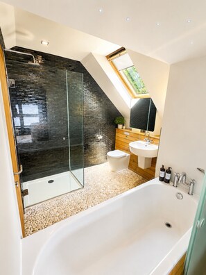 A modern bathroom with a glass-enclosed shower, a freestanding bathtub, a white toilet, and a wooden vanity with a sink. - Print Room 2 at Strattons Hotel (Hingham)