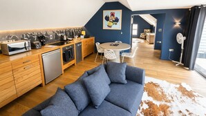 Une cuisine moderne avec des meubles en bois, un coin repas avec une table ronde et des chaises, et un salon avec un canapé bleu.