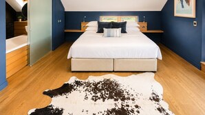 Une chambre à coucher avec un lit, un tapis en peau de vache, une table de chevet et un tableau au mur.