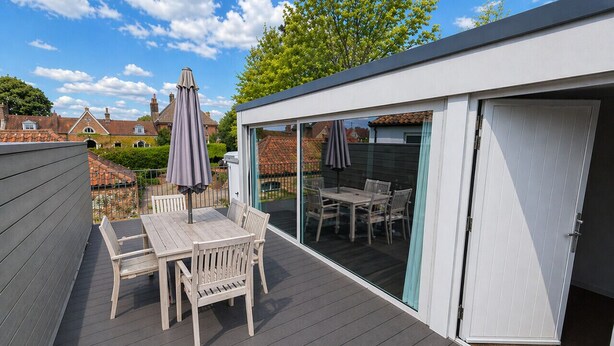 Une terrasse avec une table et des chaises, une porte-fenêtre coulissante et une vue sur un jardin.