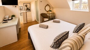 A bedroom with a bed, bedside tables, a desk, a chair, a mirror, and a window.