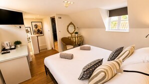 A hotel room with a bed, bedside table, and a small desk.