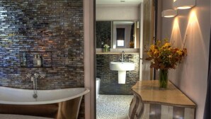 A modern bathroom with a freestanding bathtub, a vanity with a mirror, and a sink. - Cocoes ONE King Apartment at Strattons (Swaffham)