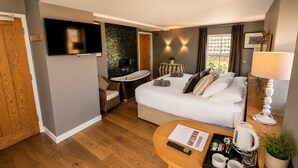 A hotel room with a bed, a TV, a bathroom, and a wooden floor. - Cocoes ONE King Apartment at Strattons (Swaffham)