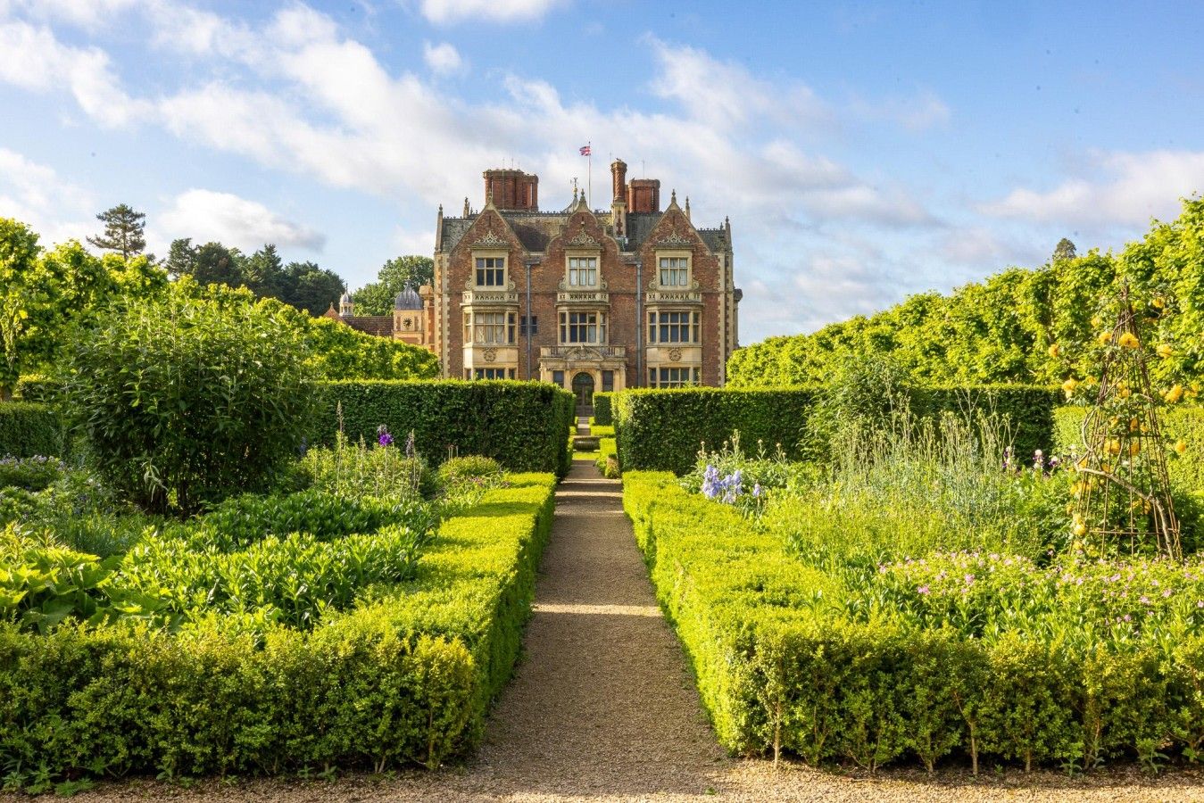 A grand building with a symmetrical garden and a central pathway leading to the entrance.