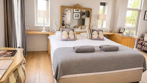 A bedroom with a large bed, bedside tables, a mirror, and a window. - Cocoes ONE King Apartment at Strattons (Swaffham)
