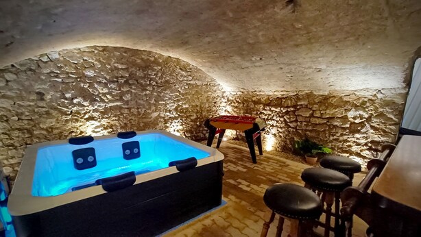 A stone-walled room with a hot tub, stools, and a foosball table. - Gite "La Greniette (Châteauneuf-sur-Loire)