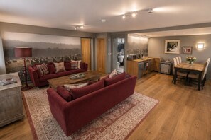 Un salon avec un canapé rouge, une table basse et un tapis. Il y a également un coin cuisine avec des meubles en bois et une table à manger.