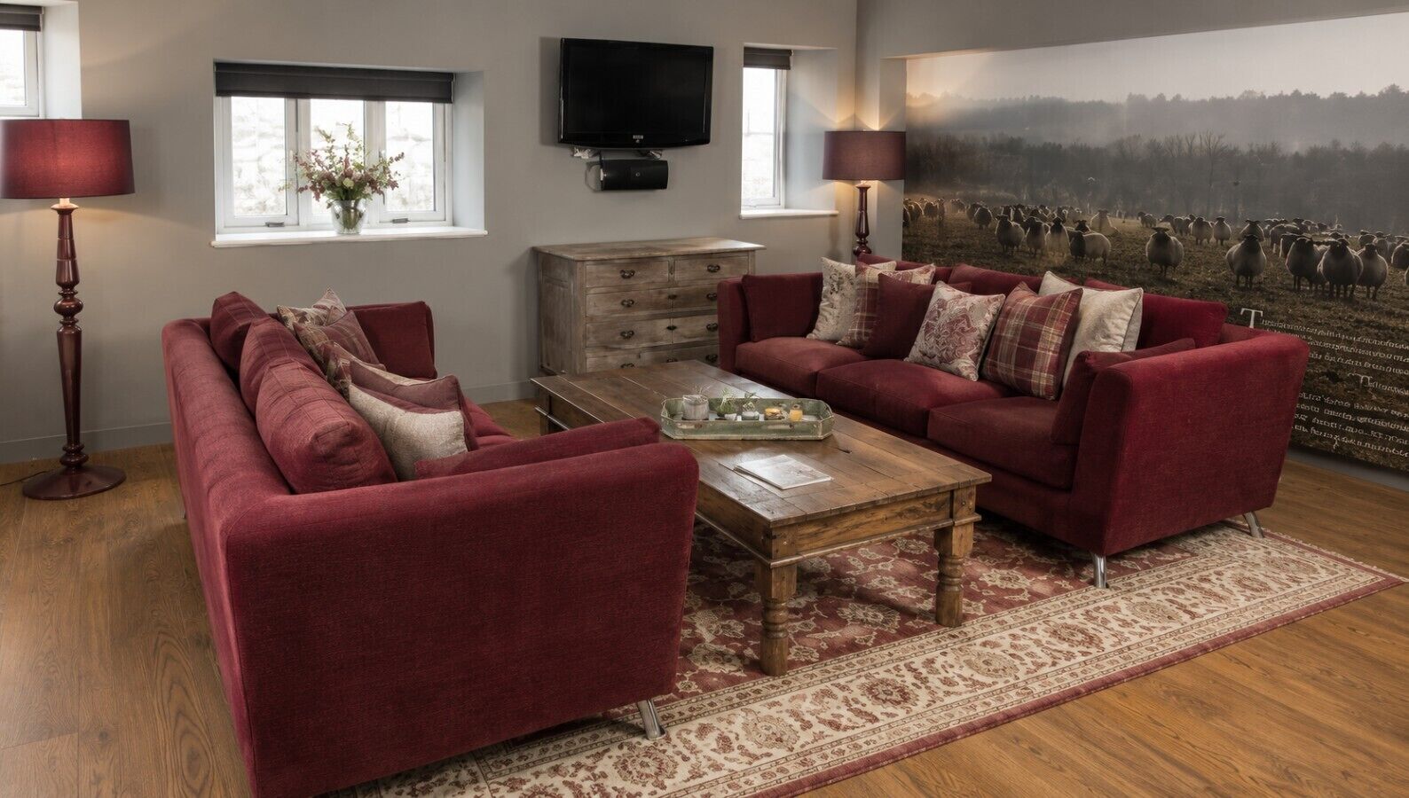 Een woonkamer met een bank, een salontafel, een televisie en een groot schilderij.