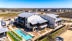 A modern multi-story residential building with a swimming pool and outdoor seating area. - Luxe Condo • Prime Location • 5-Star Comfort (New Braunfels)