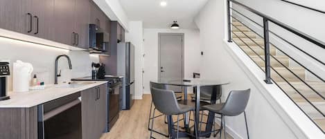 Una cocina moderna con armarios de madera oscura, un lavamanos de acero inoxidable y un comedor con dos sillas.