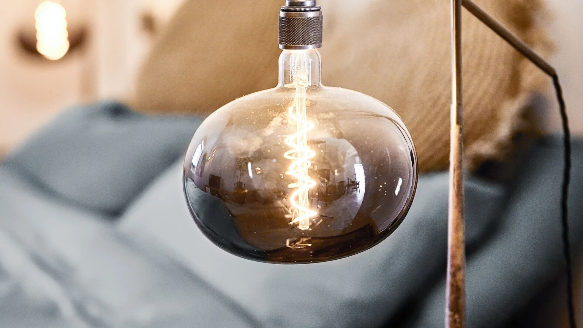 A clear glass light bulb with a visible filament, hanging from a metal fixture.