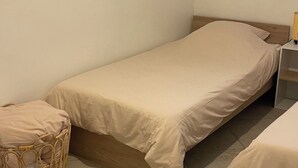 Un llit individual amb estructura de fusta i una cistella teixida a prop.