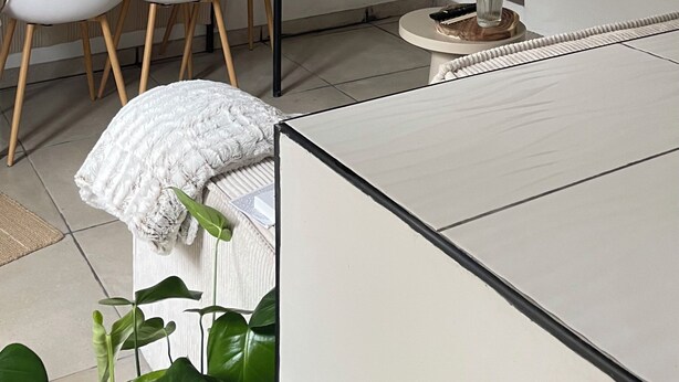 Habitació minimalista amb taula de menjador, cadires, llum penjant, obra d'art emmarcada i una planta.