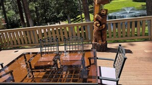 A wooden deck with a grill, chairs, and a bear statue. - Innsbrook Vacation Townhome 57 (Ruidoso)