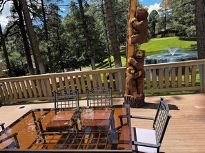 Eine Holzterrasse mit Grill, Stühlen und einer Bärenstatue.