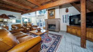 A spacious living room with a fireplace, leather sofas, a television, and a patterned rug. - Innsbrook Vacation Townhome 57 (Ruidoso)