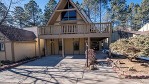 A two-story building with a balcony, a covered walkway, and a landscaped area with trees and shrubs. - Innsbrook Vacation Townhome 57 (Ruidoso)