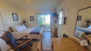 Een slaapkamer met twee bedden, een houten tafel en een schommelstoel.