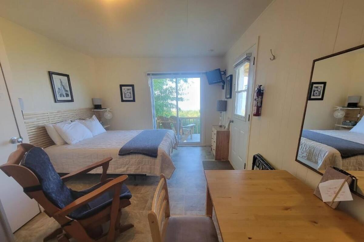 Un dormitorio con dos camas, una mesa de madera y un sillón mecedor.