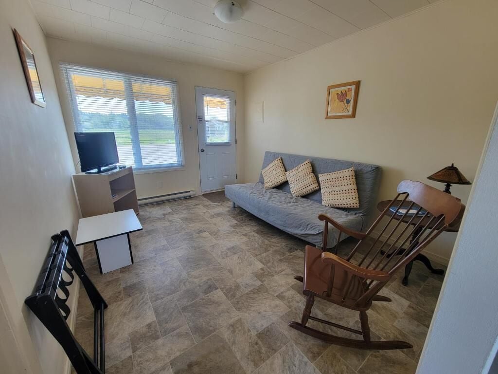 A living room with a sofa, a rocking chair, a television, and a door.