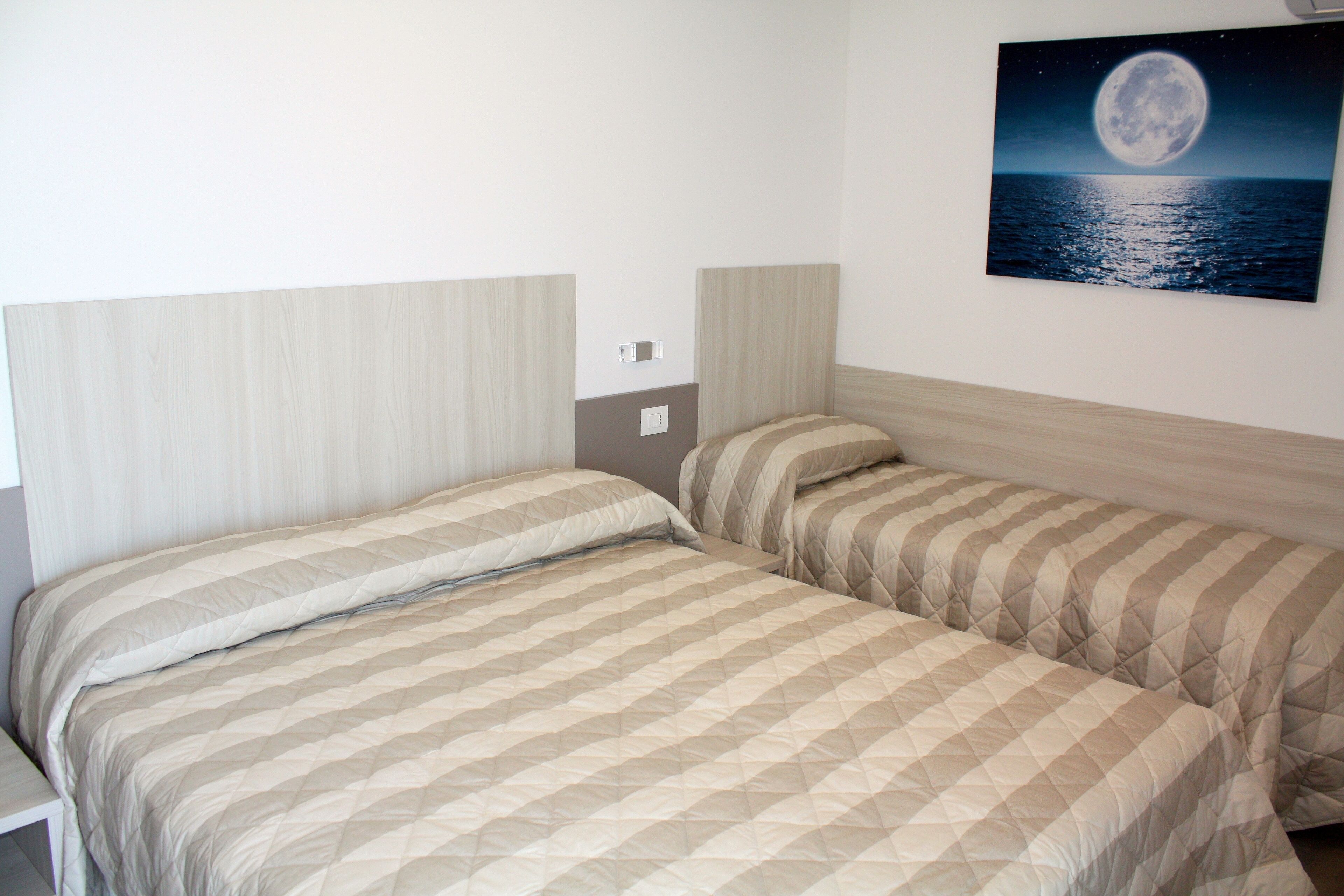 A twin room with two beds, a night sky mural, and a view of the sea.