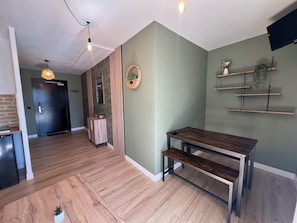 Un interno moderno con pavimento in legno, una porta scura, un tavolino e una mensola a muro.
