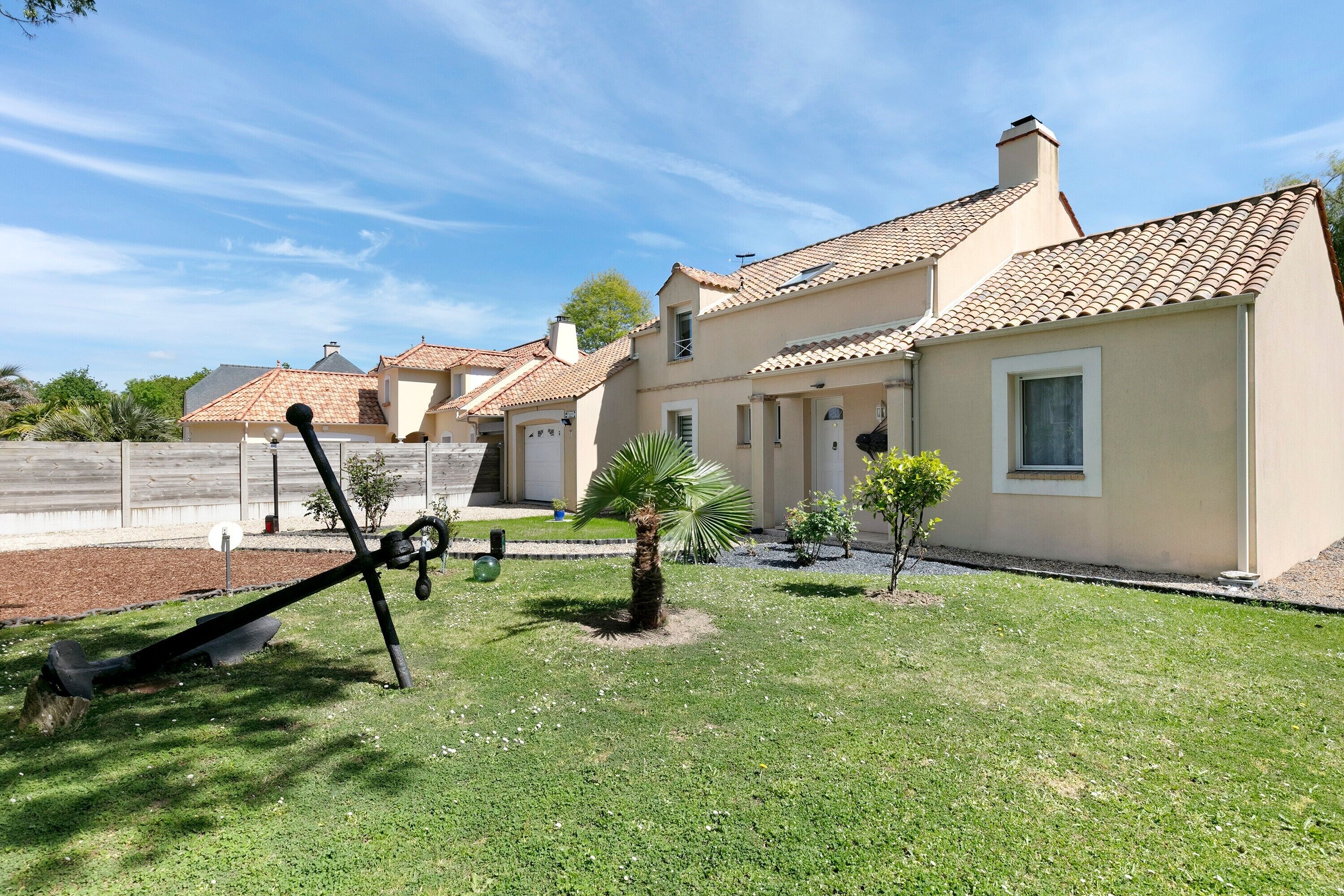 A residential property with a well-maintained lawn, a palm tree, and a patio area.
