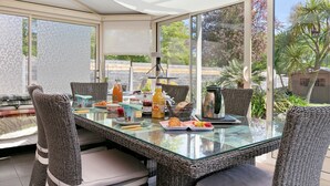 Un comedor con sillas de mimbre, una mesa de vidrio y diferentes opciones para el desayuno.
