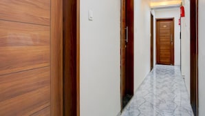 Un pasillo con puertas de madera, suelo de mármol y un extintor en la pared.