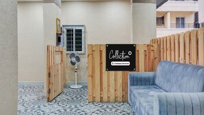 Habitación con sofá azul, un ventilador, un separador de madera y un letrero que dice 'Collection Company-Serviced'.