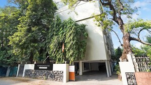 A building labeled 'TOWNHOUSE & Company Service' with a stone wall entrance, large trees, and a clear sky. - Super Deluxe Octave Parkland Suites (Nagpur)