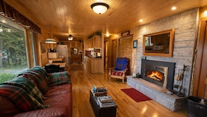 Ein gemütliches Blockhaus-Interieur mit Ledersofa, Kamin, Essbereich und Küche.