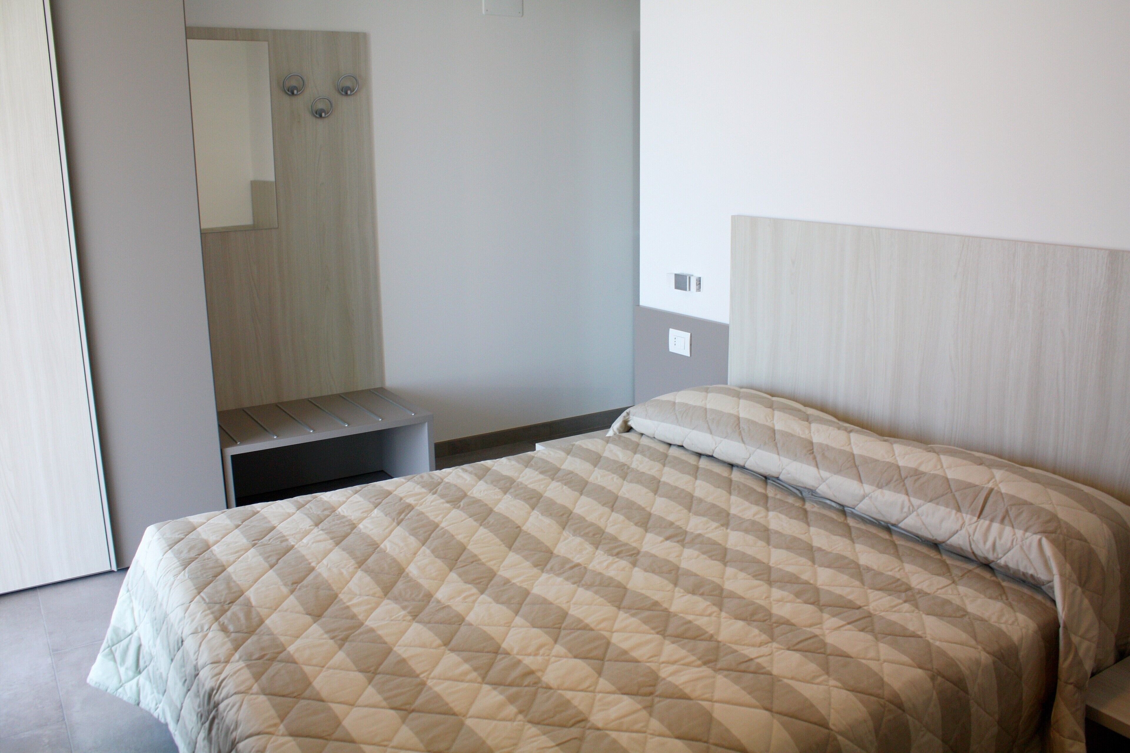 Une chambre à coucher avec un lit, une table de chevet et un miroir.