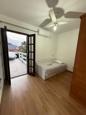 A bedroom with a bed, a ceiling fan, and an open door leading to a balcony. - Vacation home with a pool, just 150 meters from the beach in Piratininga (Niterói)