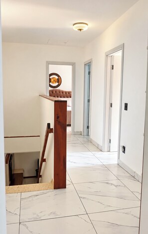 A hallway with a wooden staircase, a record wall art, and a door leading to another room. - Vacation home with a pool, 150 m from the beach in Piratininga (Niterói)