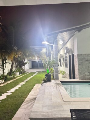 A pool area with a stone pathway leading to the pool, surrounded by potted plants and a small garden. - Vacation home with a pool, just 150 meters from the beach in Piratininga (Niterói)