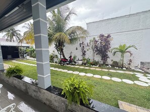 A courtyard with a paved walkway, palm trees, and a white wall. - Vacation home with a pool, just 150 meters from the beach in Piratininga (Niterói)