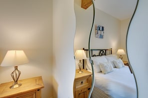 Hotelkamer met een bed, twee nachtkastjes met lampen, een houten bijzettafeltje en een kunstwerk aan de muur.